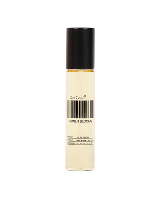 A clear cylindrical rollerball bottle with a black cap, containing a pale yellow liquid. The label reads 'DeeCool' and 'SUNLIT BLOOMS' with a barcode graphic, set against a plain white background.